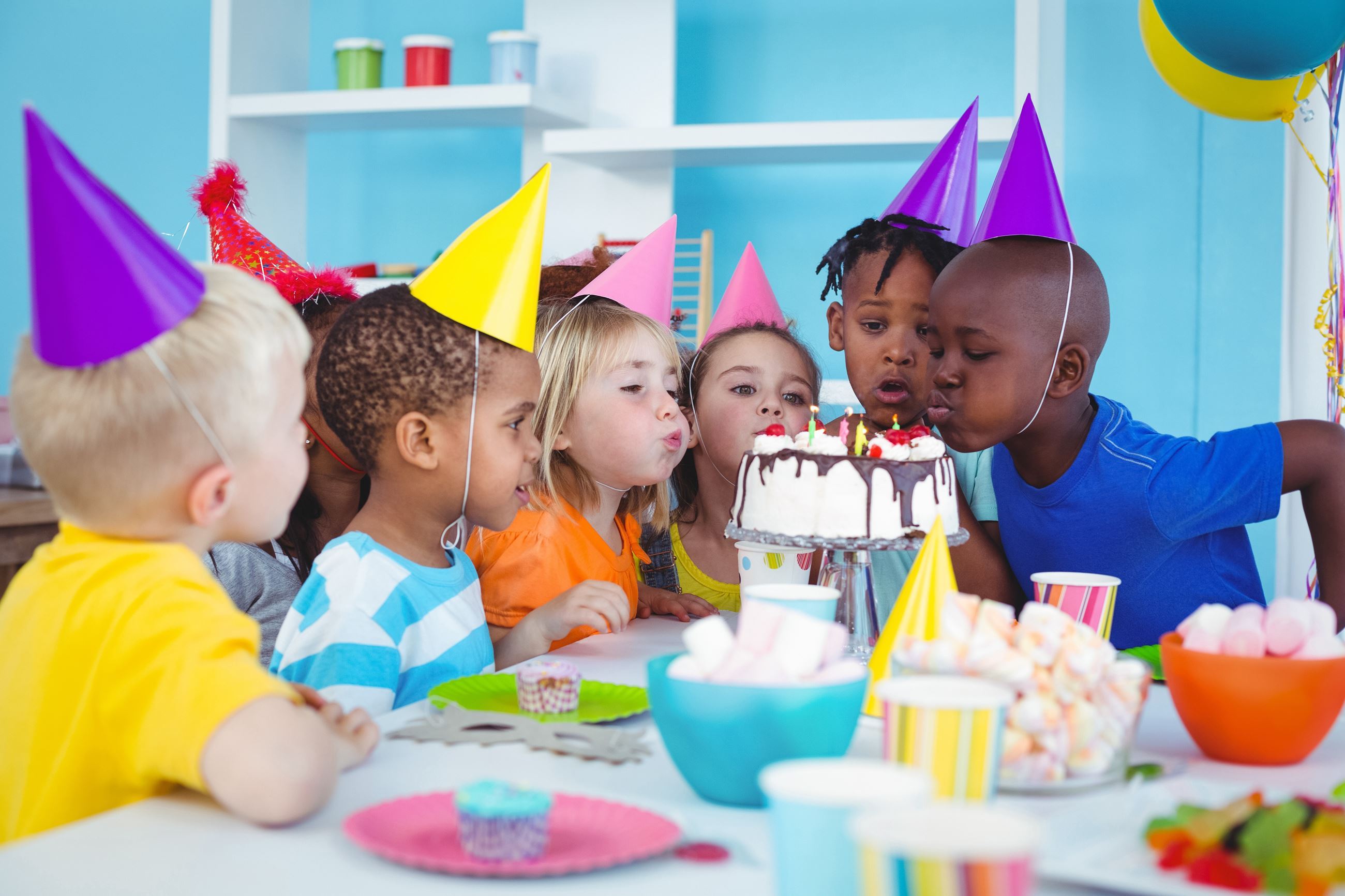 Kid's birthday party: child blowing out candle on cake